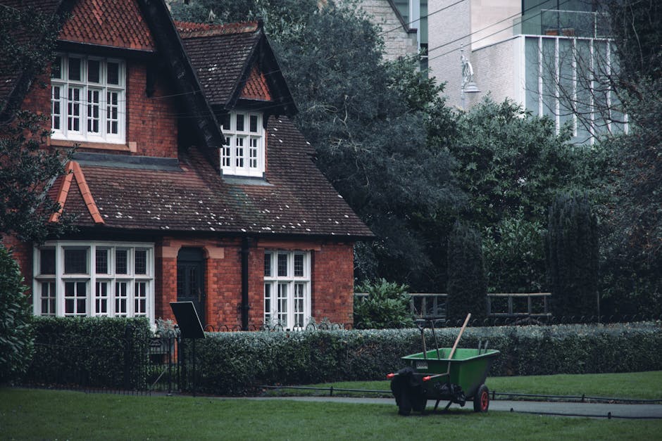 A traditional brick house with a steeply pitched roof covered in dark dorsal tiles, featuring white-framed sash windows on the ground and upper floors. In the front garden, there is a well-maintained